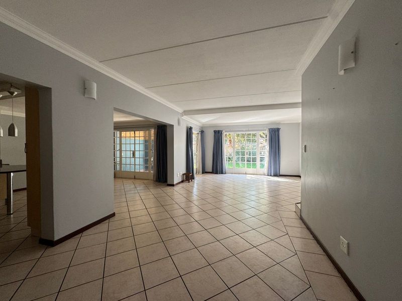 Spacious open-plan living area featuring neutral tiled flooring, classic cove cornicing, and large french doors providing natural light and garden access.
