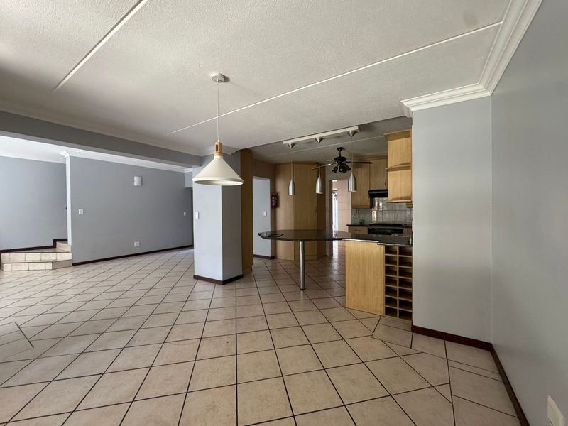 Spacious open-plan living and kitchen area featuring tiled floors, built-in cabinetry, a breakfast bar, and integrated wine storage.