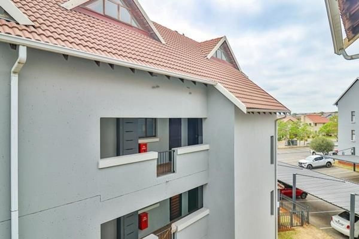 Exterior view of the apartment building featuring a tiled roof, balcony access, and visible fire safety equipment.