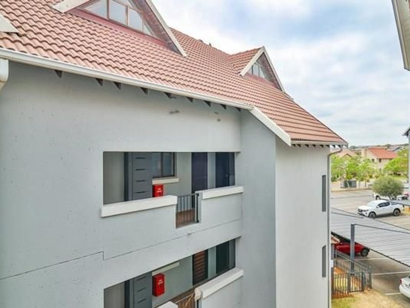 Exterior view of the apartment building featuring a tiled roof, balcony access, and visible fire safety equipment.