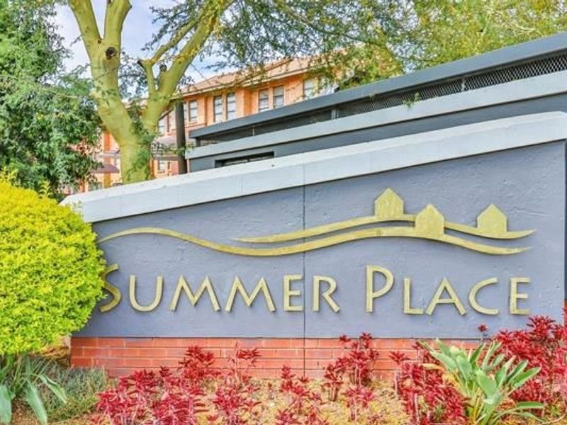 Entrance signage for Summer Place apartment complex, featuring a brick and rendered wall with established garden landscaping.