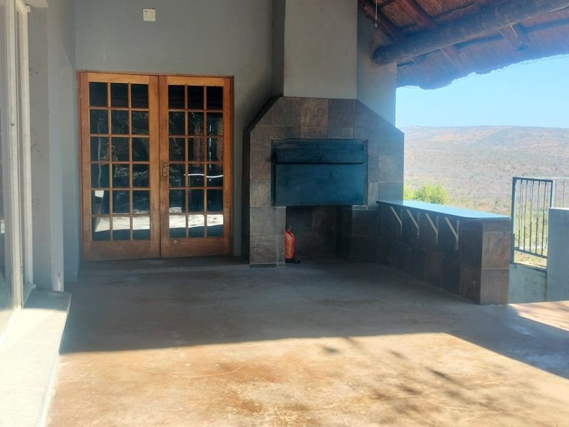 Covered patio area featuring a built-in braai, tiled prep counter, and scenic landscape views, perfect for outdoor entertaining.