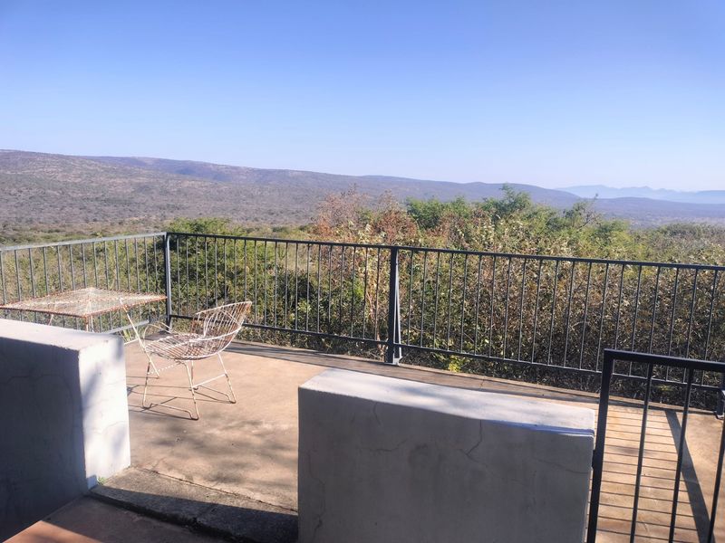 An elevated outdoor balcony featuring a metal balustrade and expansive views of the surrounding landscape.
