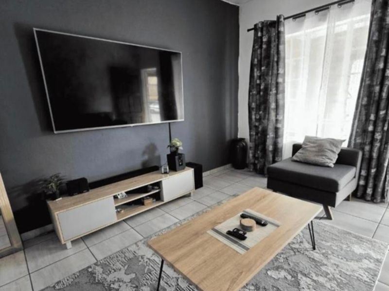 A modern living room featuring tiled flooring and a dark accent wall, providing a comfortable and contemporary space.