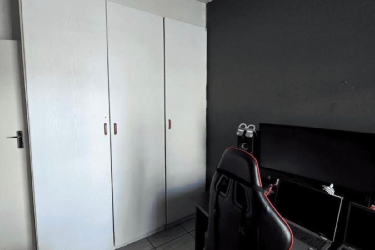 A bedroom featuring built-in wardrobes and tiled flooring, currently utilized as a home office space.