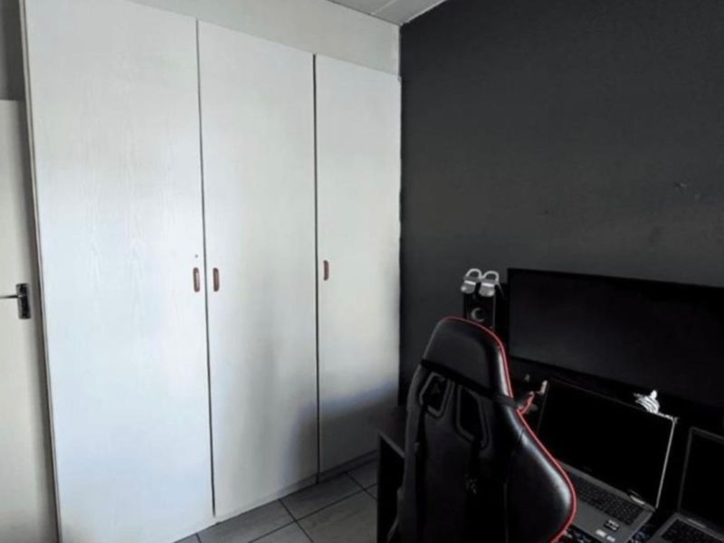 A bedroom featuring built-in wardrobes and tiled flooring, currently utilized as a home office space.