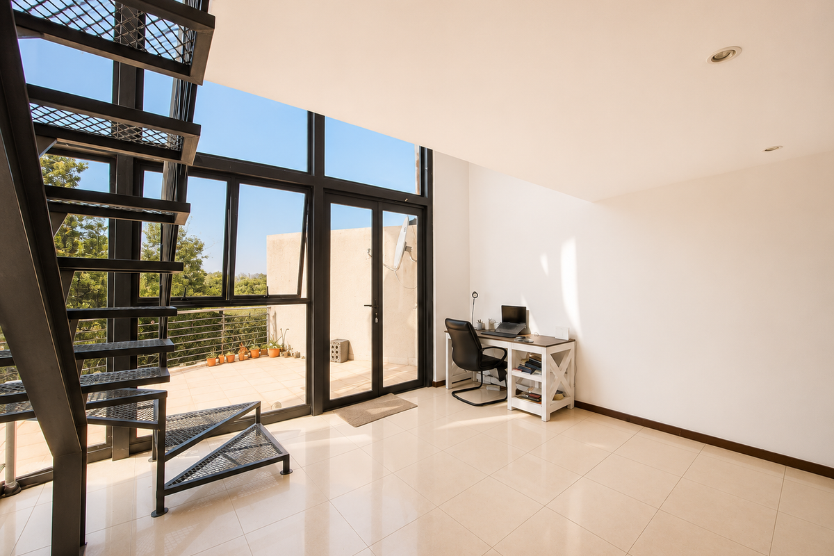 Bright living area featuring a modern metal spiral staircase, large floor-to-ceiling windows, and direct access to an outdoor balcony space.