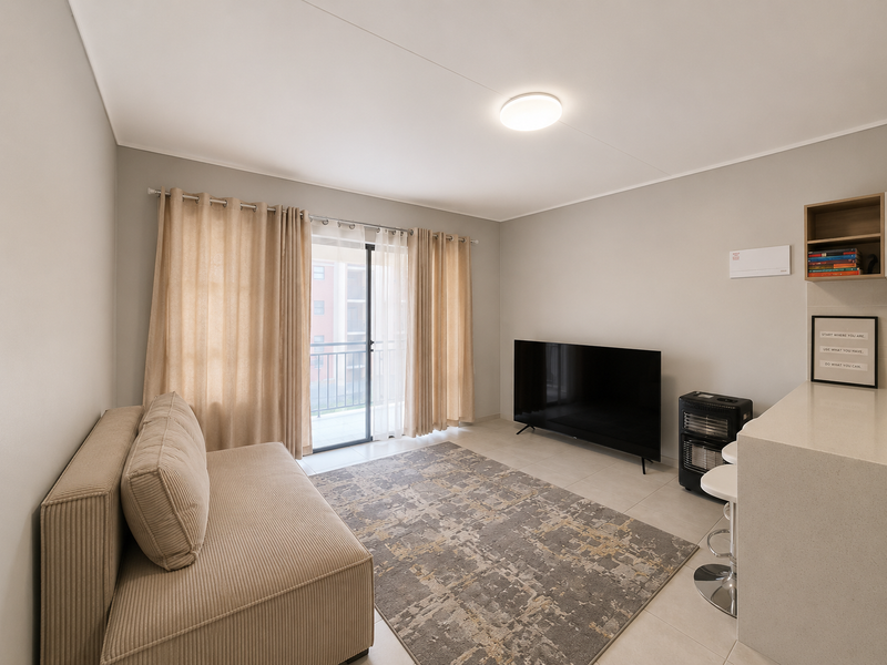 A bright and well-maintained living room featuring tiled flooring, a sliding glass door leading to a balcony, and built-in shelving.