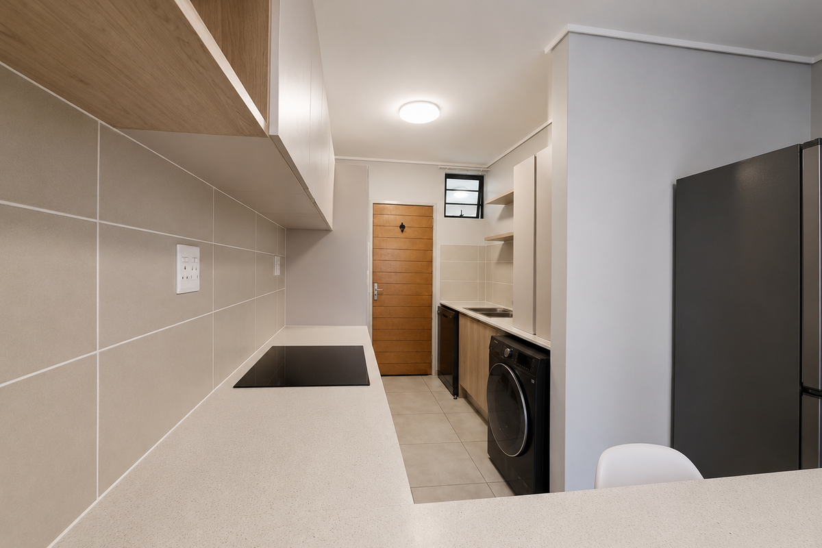 Modern kitchen featuring sleek cabinetry, stone countertops, an electric hob, and a tiled backsplash, offering a clean and functional workspace.