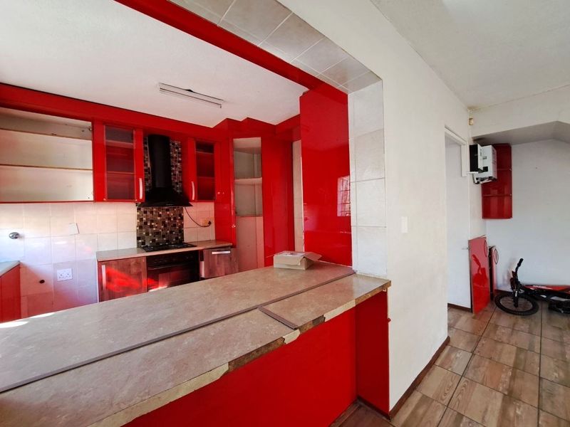 Kitchen featuring red cabinetry, a breakfast bar, and built-in appliances. The space requires cosmetic updates to the countertops and cabinetry finish.