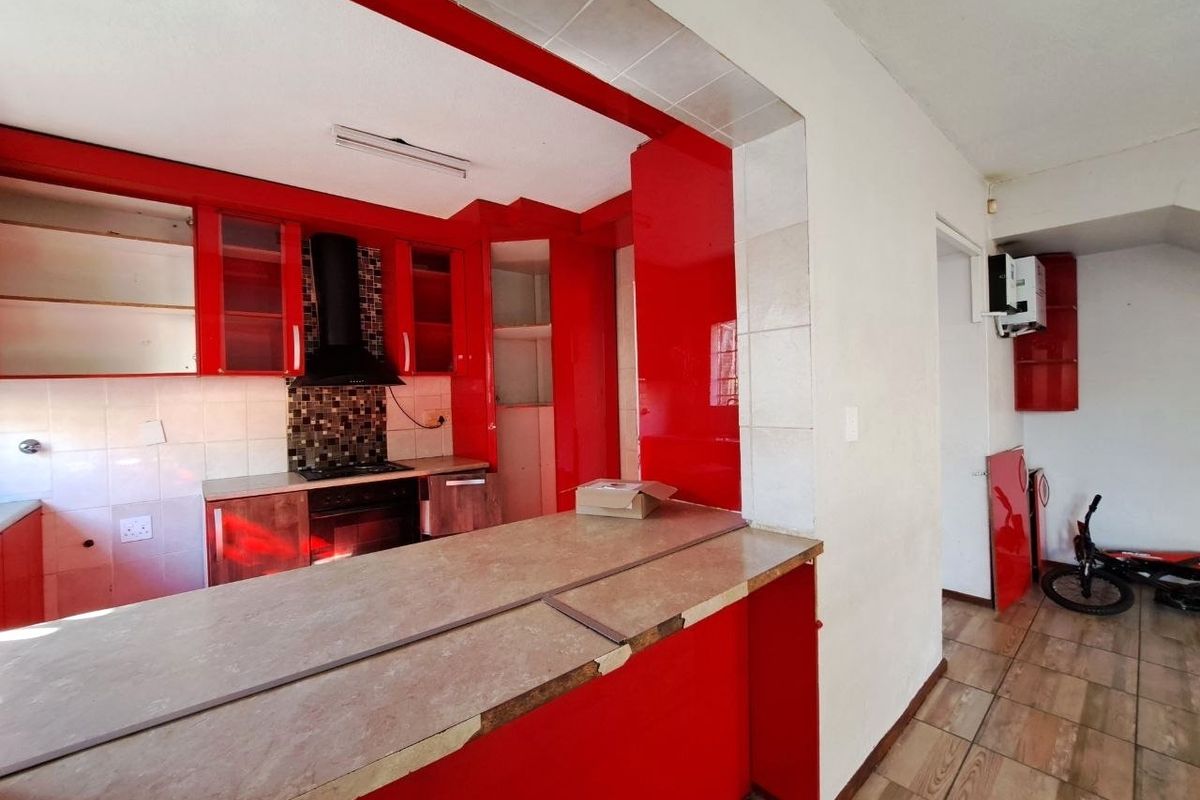 Kitchen featuring red cabinetry, a breakfast bar, and built-in appliances. The space requires cosmetic updates to the countertops and cabinetry finish.
