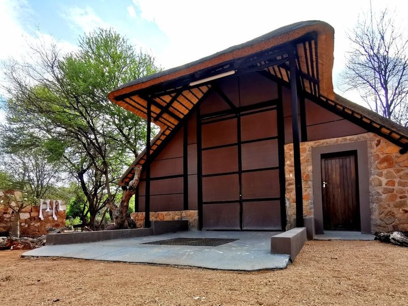 A well-maintained farm building featuring a traditional thatch roof, stone masonry accents, and a large industrial-style sliding door entrance.