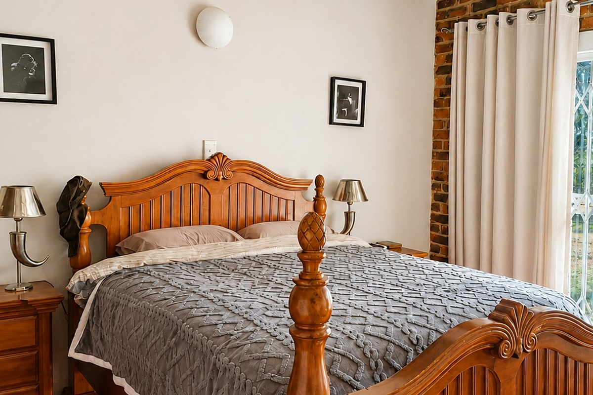 A cozy bedroom featuring an exposed brick accent wall, natural light through a sliding glass door, and a secure metal gate.