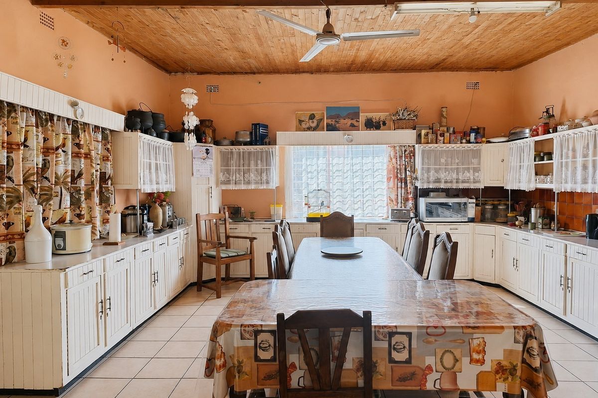 Spacious farmhouse kitchen featuring extensive built-in cabinetry, tiled flooring, and a timber-clad ceiling with a central ceiling fan.