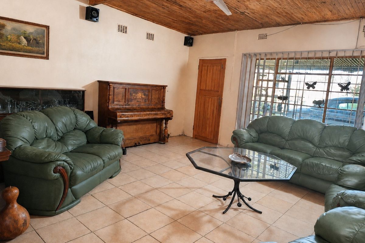 Spacious living room featuring a timber-clad vaulted ceiling, ceiling fan, and ceramic tiled flooring with large windows and security bars.