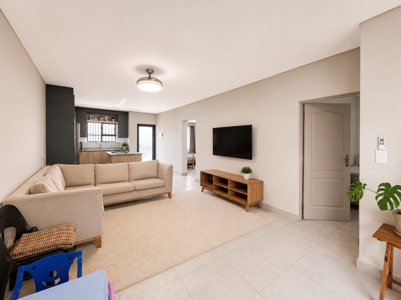 Spacious open-plan living area featuring a modern kitchen with island, neutral tiled flooring, and seamless flow into adjacent rooms.