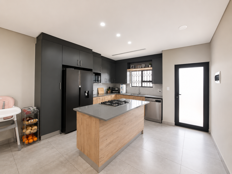 Modern kitchen featuring two-tone cabinetry, a central island with a gas hob, stone countertops, and direct access to the exterior.