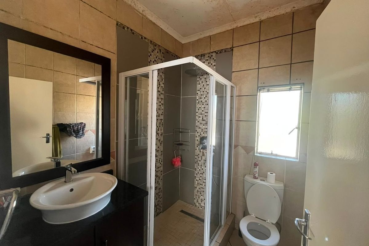 Bathroom featuring a shower enclosure, vanity basin with cabinet, and toilet, with visible ceiling water damage requiring maintenance.