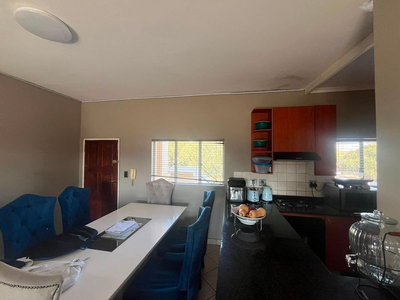 Open-plan kitchen and dining area featuring granite countertops, built-in cabinetry, and a gas hob, with visible ceiling water staining.
