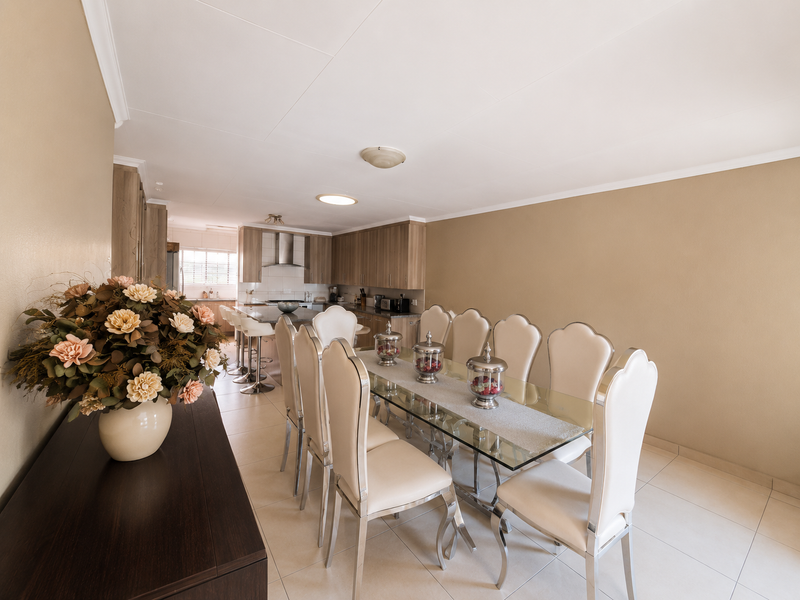 Open-plan dining and kitchen area featuring tiled flooring, modern cabinetry, and a central kitchen island with integrated appliances.