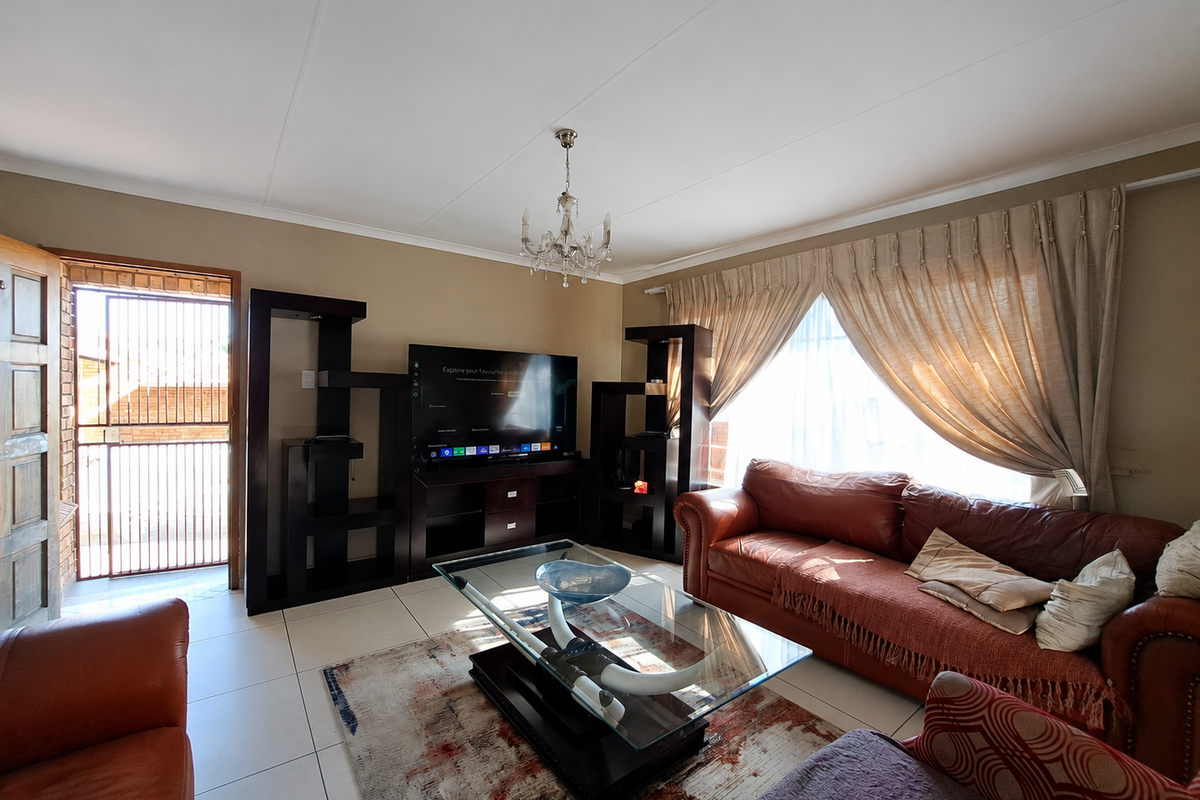 A comfortable living room featuring tiled flooring, a central chandelier, and direct access to an exterior security gate.