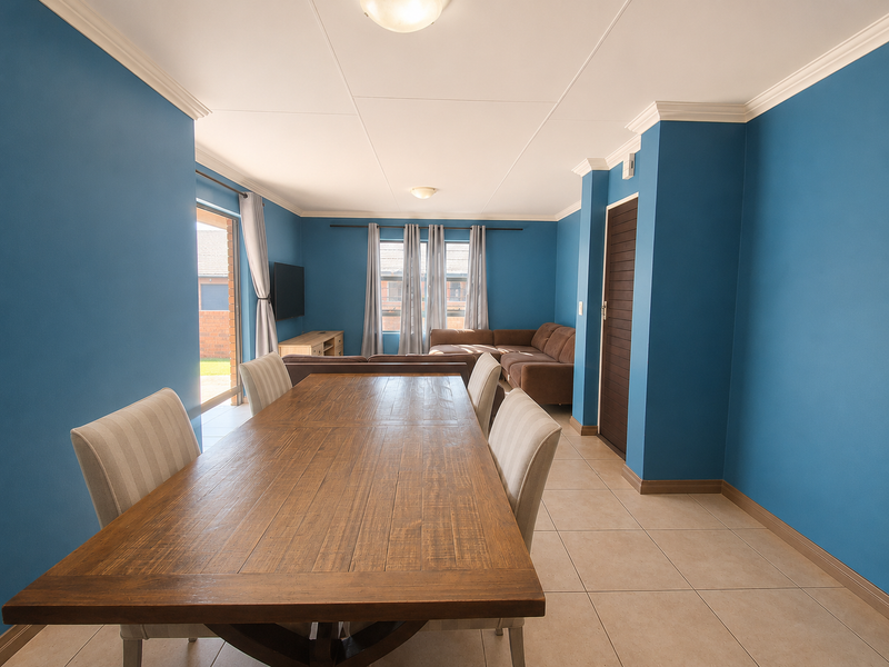 An open-plan living and dining area featuring tiled flooring, crown molding, and a sliding glass door providing access to the exterior.
