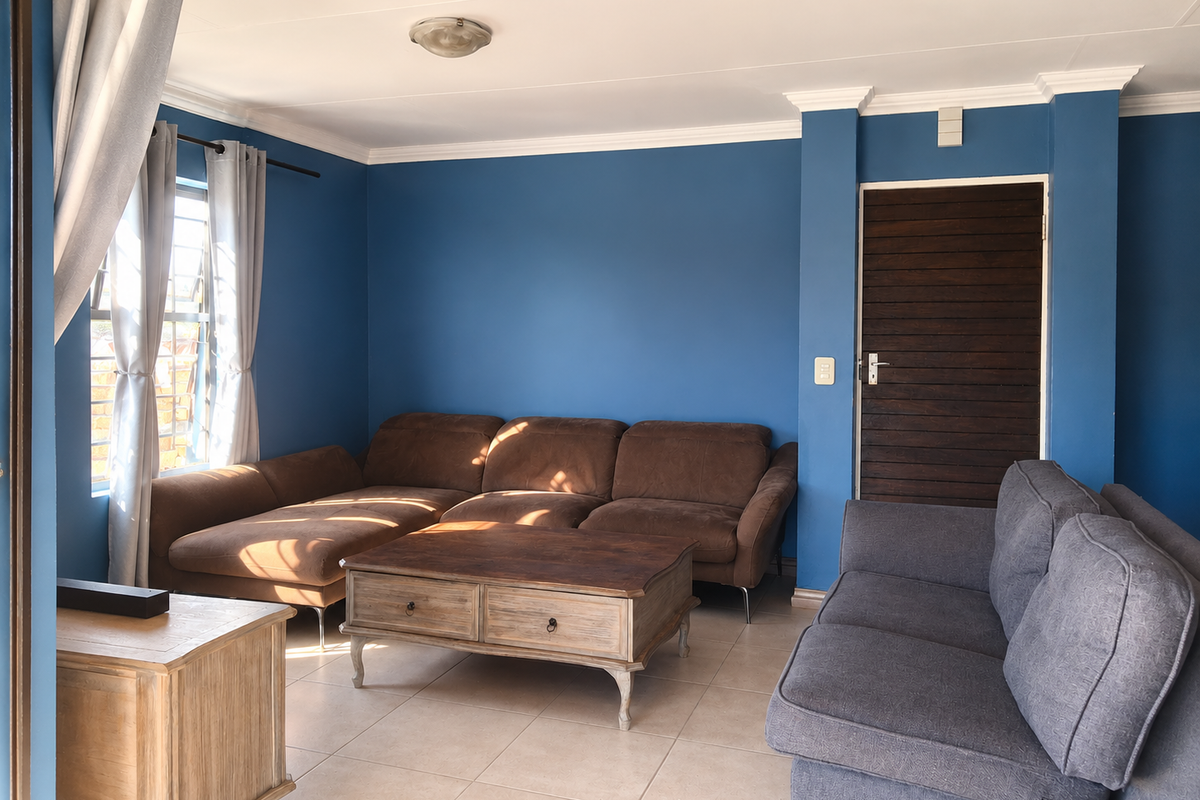 A living room featuring blue painted walls, tiled flooring, crown molding, and a horizontal slat timber door.