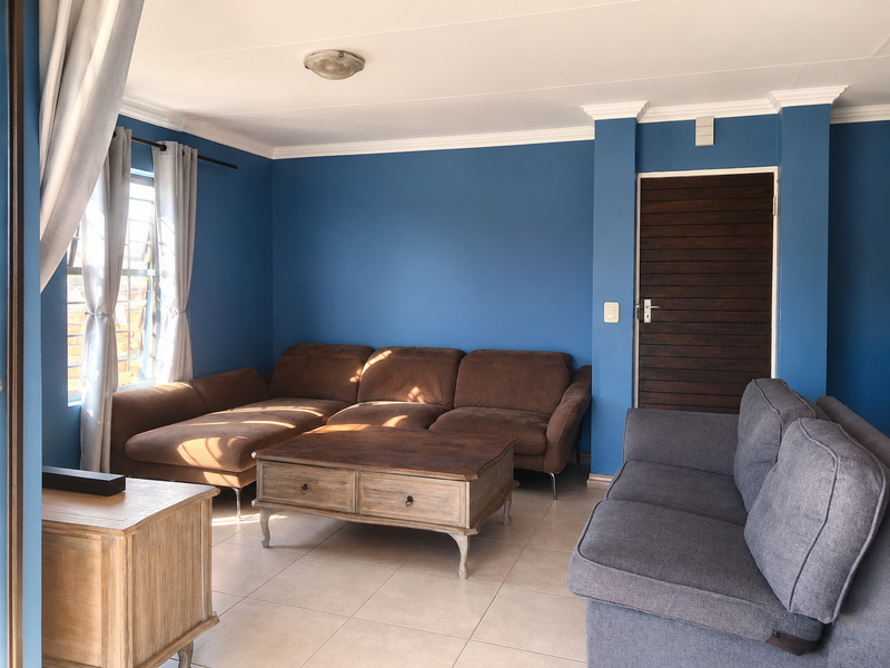 A living room featuring blue painted walls, tiled flooring, crown molding, and a horizontal slat timber door.