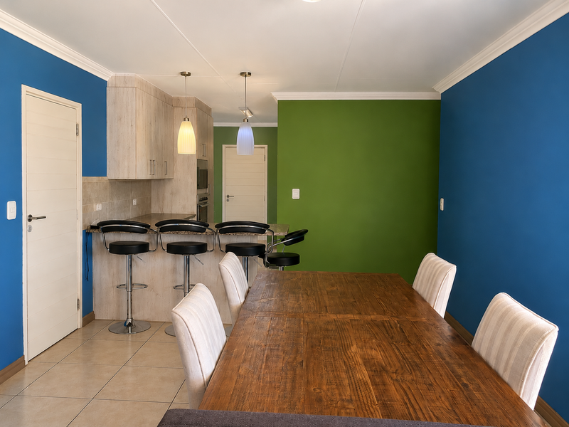 Open plan dining and kitchen area featuring a breakfast bar, tiled flooring, and vibrant accent walls.