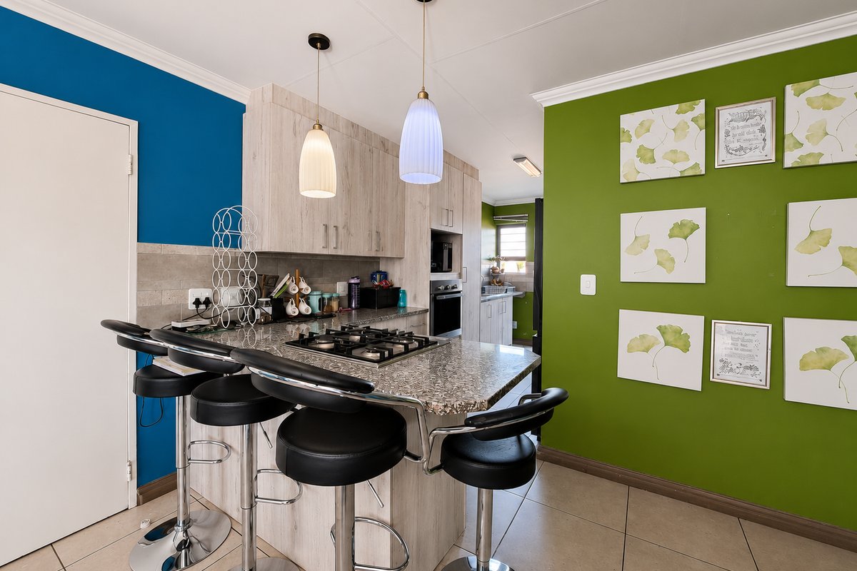Modern kitchen featuring a central island with a built-in gas hob, granite countertops, tiled flooring, and contemporary cabinetry with integrated appliances.