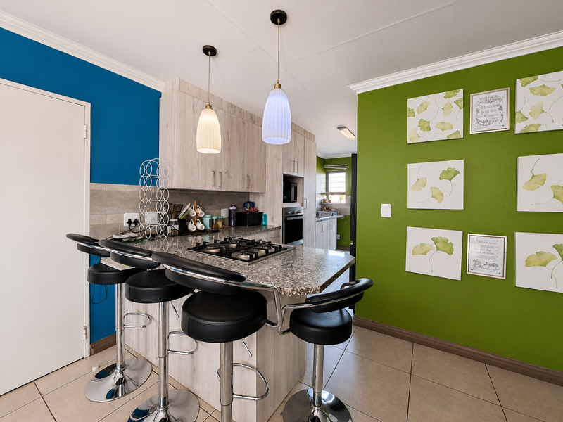 Modern kitchen featuring a central island with a built-in gas hob, granite countertops, tiled flooring, and contemporary cabinetry with integrated appliances.