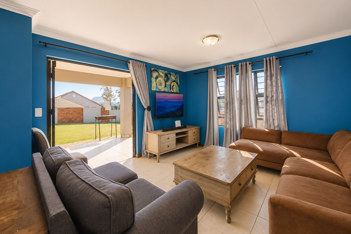 A bright living room featuring tiled flooring, coved ceilings, and large sliding glass doors that provide seamless access to the outdoor patio area.