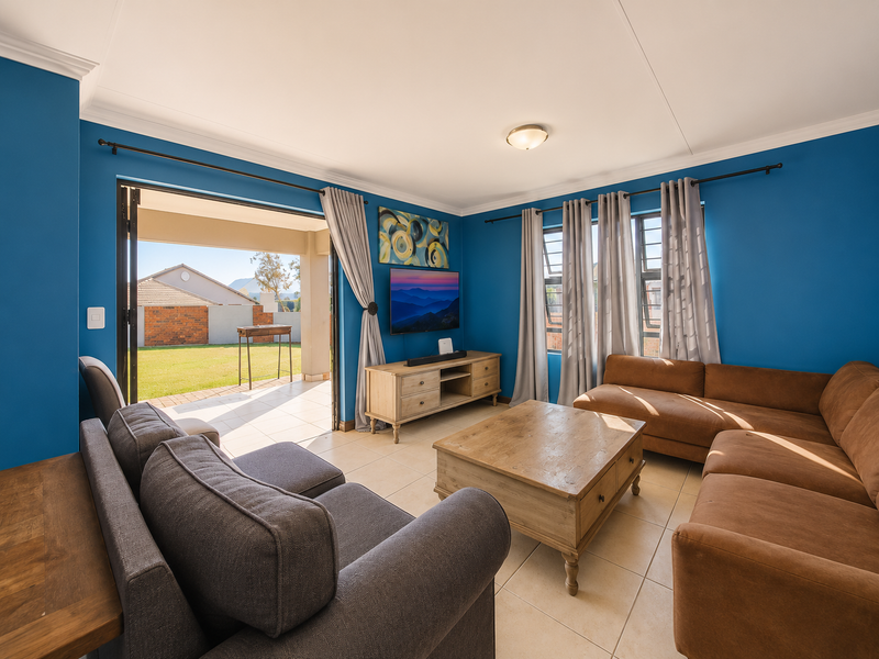 A bright living room featuring tiled flooring, coved ceilings, and large sliding glass doors that provide seamless access to the outdoor patio area.