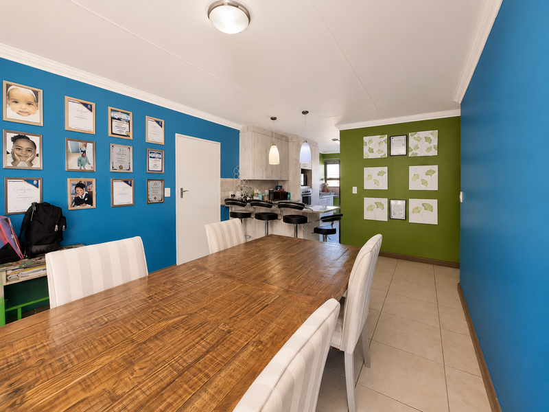 Open plan dining and kitchen area featuring a breakfast bar, tiled flooring, and vibrant feature walls, creating a functional and connected living space.