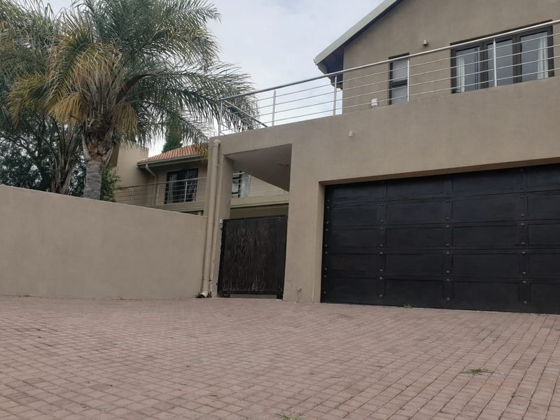 Front exterior view of the property featuring a paved driveway, double garage, and an upper-level balcony with stainless steel railings.