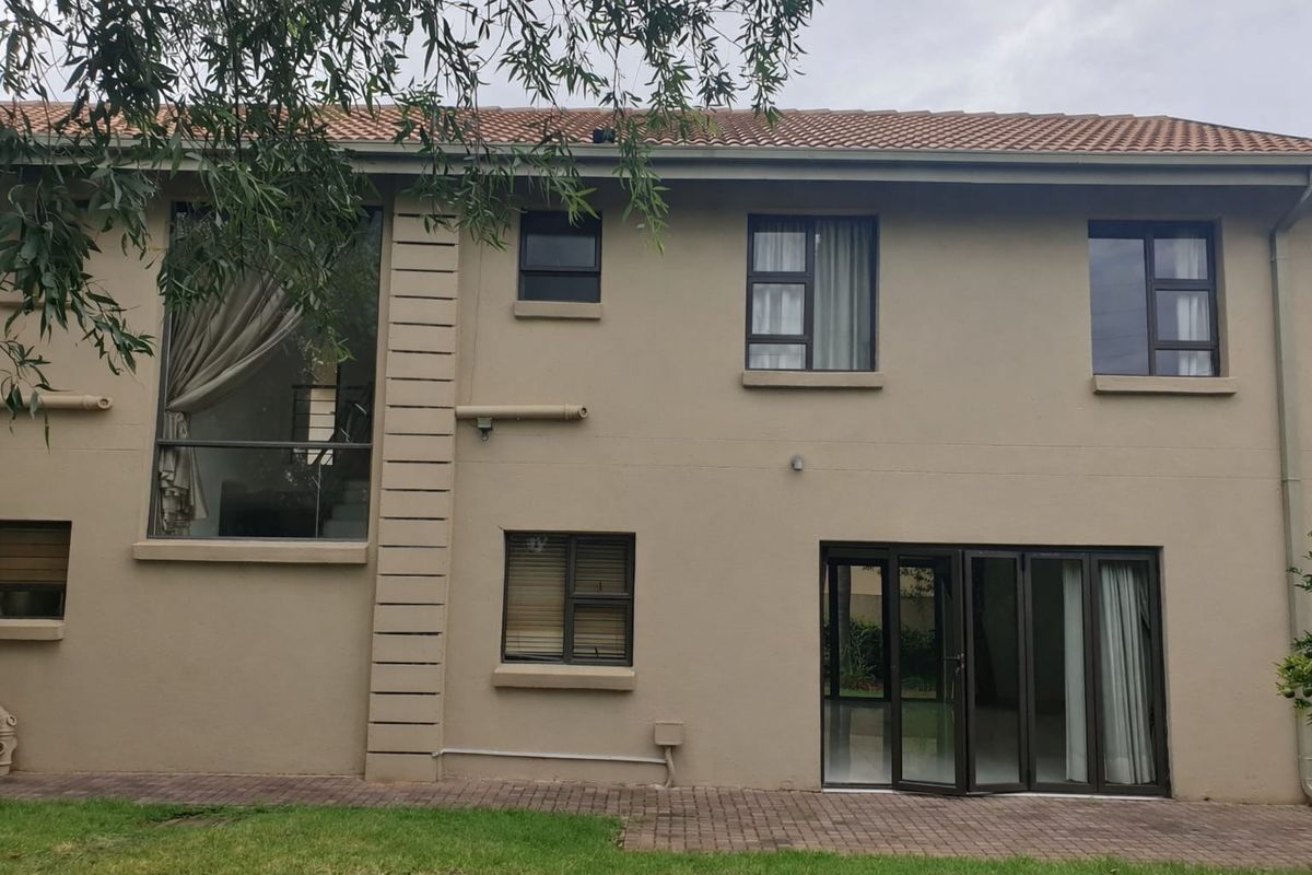 Rear elevation of a two-story house featuring a paved patio, bi-fold doors, and modern aluminium window frames.