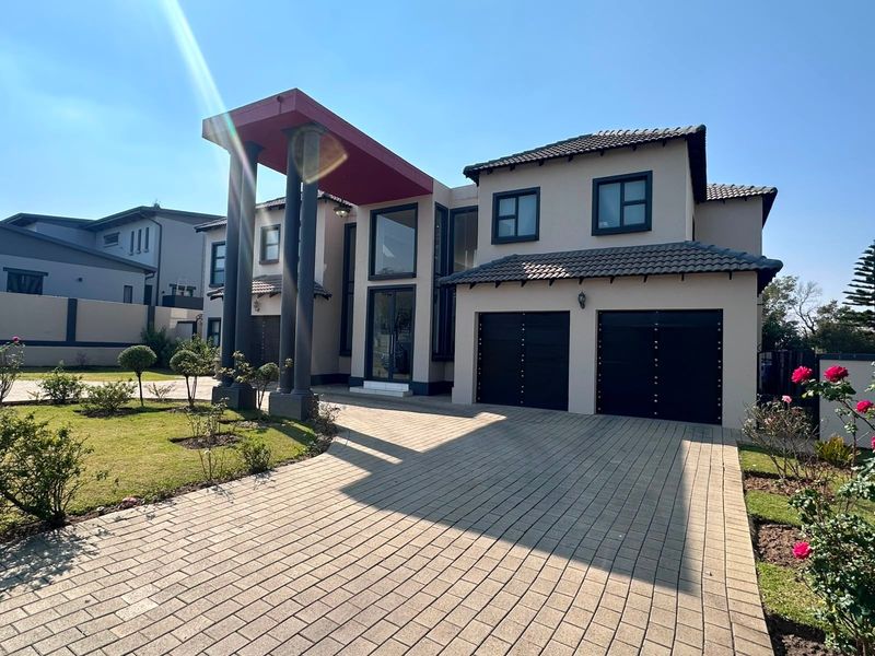 Modern double-story residential home featuring a paved driveway, double garage, and a prominent covered entrance with structural columns.
