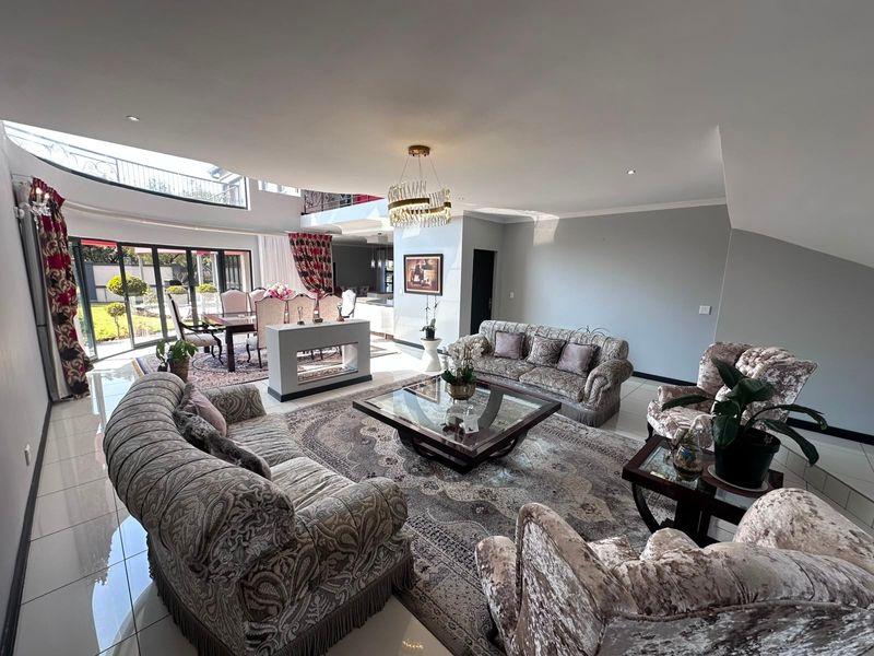 Spacious open-plan living and dining area featuring high ceilings, tiled floors, a modern fireplace, and large bi-fold doors opening to the garden.