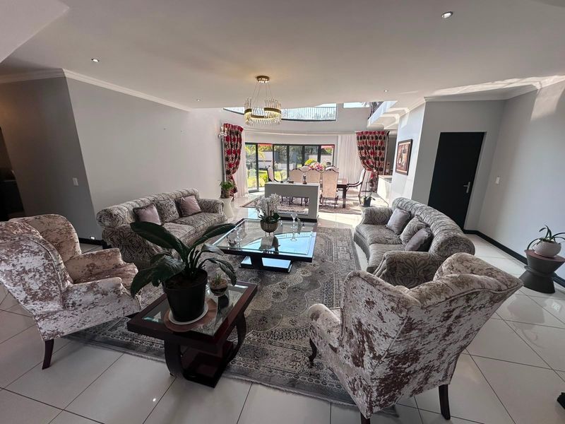 Spacious open-plan living and dining area featuring tiled floors, recessed lighting, a double-volume ceiling, and large sliding glass doors leading to the outdoors.