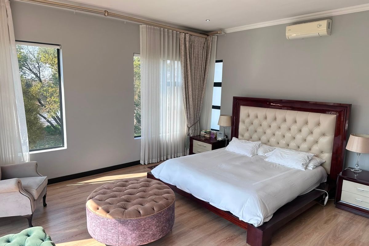 Spacious bedroom featuring laminate flooring, recessed lighting, and a wall-mounted split-system air conditioner, offering a bright and comfortable living space.