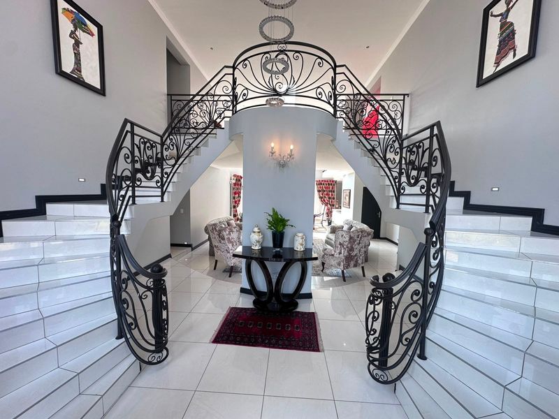 Grand entrance hall featuring a symmetrical dual staircase with ornate wrought iron railings and polished tiled flooring.