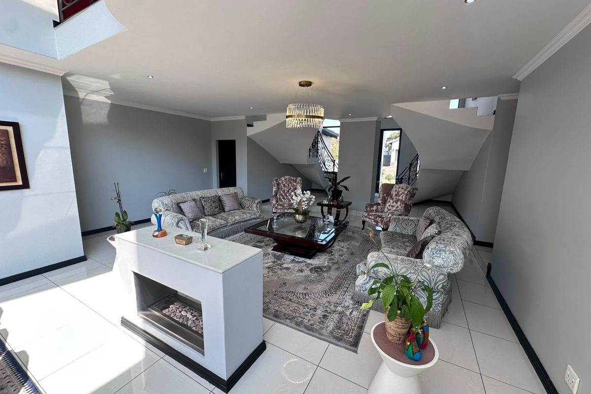 Spacious living room featuring a modern double-sided fireplace, tiled flooring, recessed lighting, and an elegant staircase with a wrought iron balustrade.