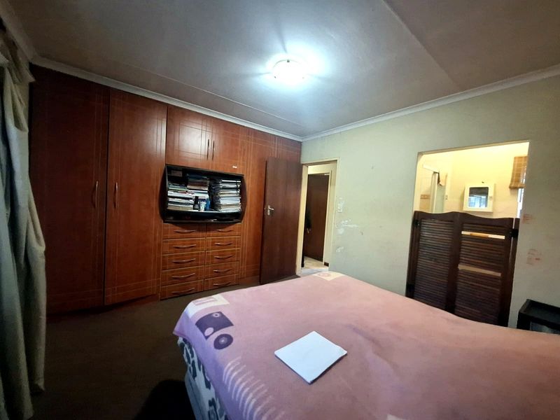 Bedroom featuring extensive built-in wooden cabinetry and direct access to an en-suite bathroom area.