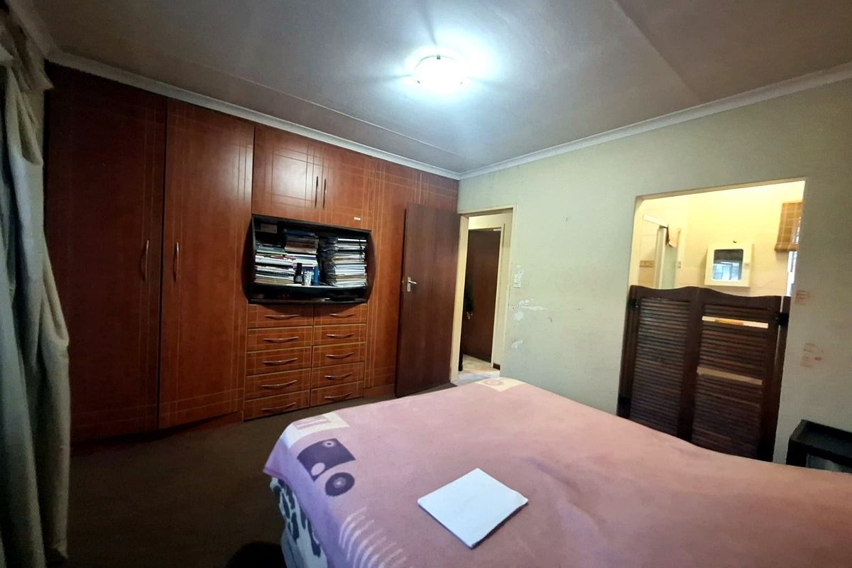 Bedroom featuring extensive built-in wooden cabinetry and direct access to an en-suite bathroom area.