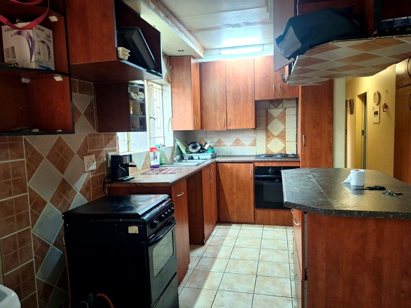 A functional kitchen featuring wood-look laminate cabinetry, tiled backsplash, built-in oven, and a breakfast bar, offering potential for a modern cosmetic update.