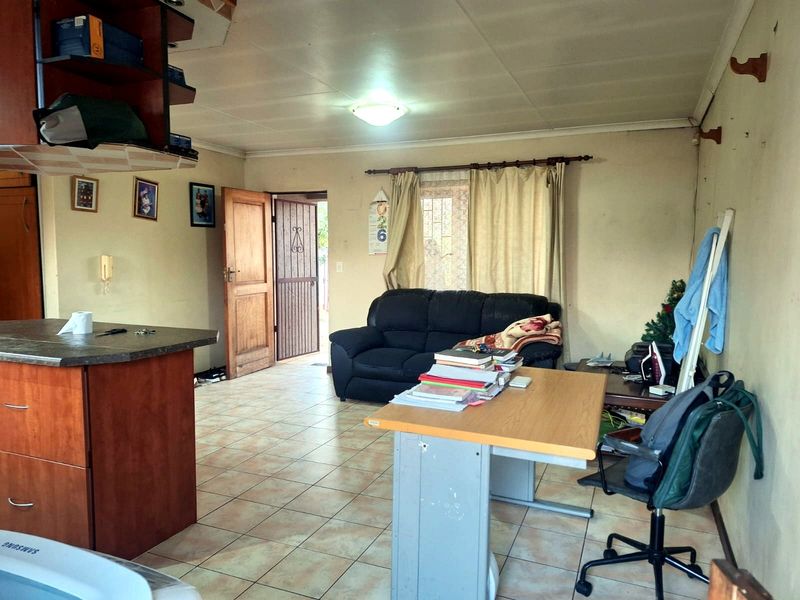 Open-plan living area featuring tiled flooring and a kitchen island, providing a functional layout with direct access to the exterior.