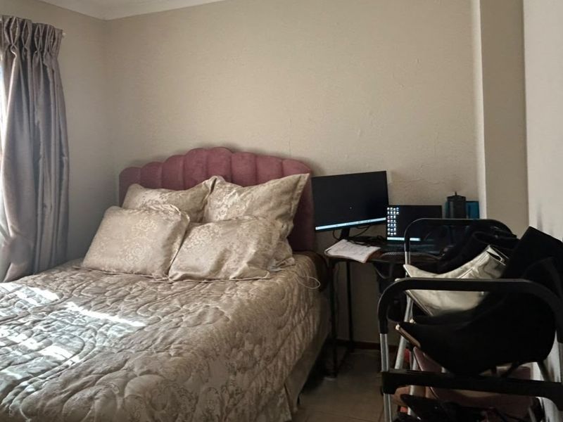 A bedroom featuring neutral wall finishes and coving, showing visible signs of plaster cracking on the wall surface.