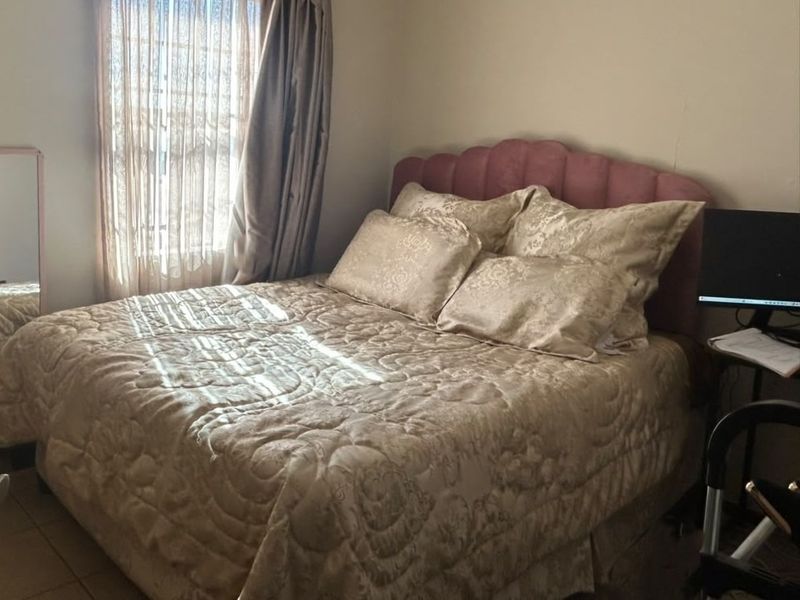 A bedroom featuring tiled flooring and natural light from a window with curtains.