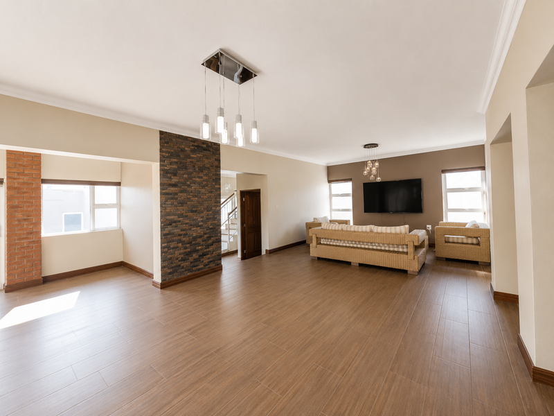 Spacious living area featuring wood-look tile flooring, a striking stone feature wall, exposed brick accents, and modern pendant lighting.