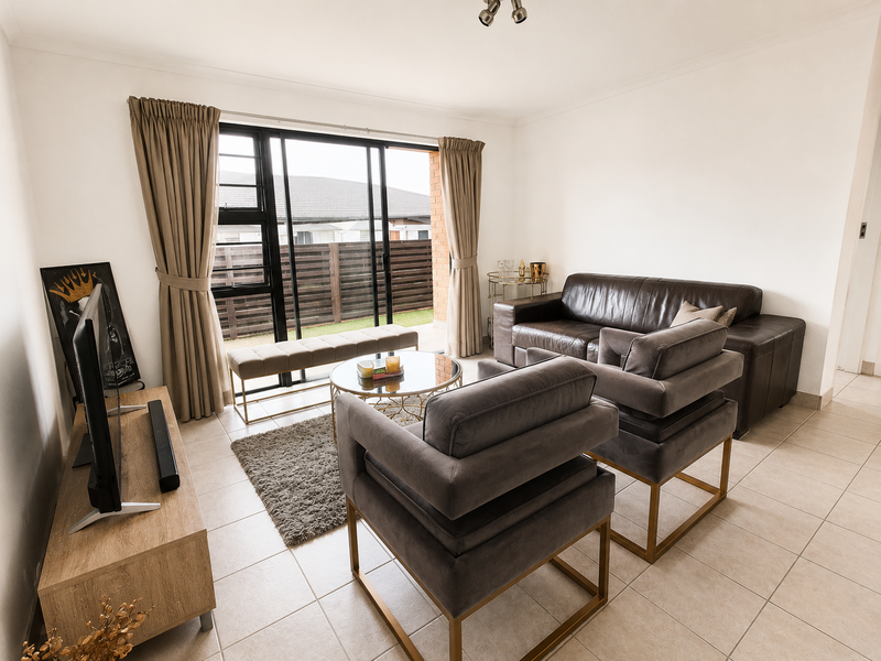 A bright living room featuring tiled flooring and a large sliding glass door providing access to the outdoor area.